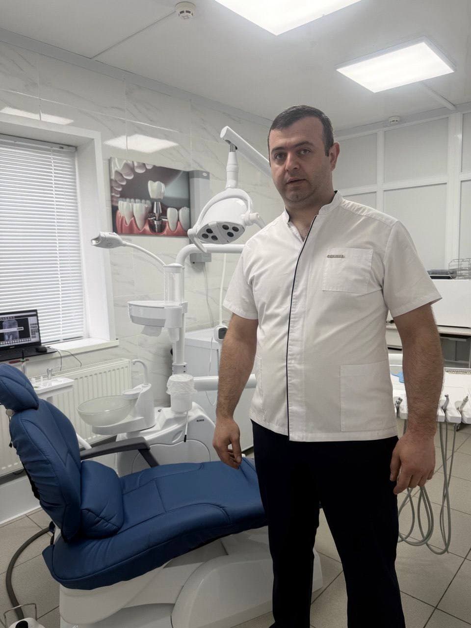 Стоматолог Бархударян Геворг Варужанович в кабинете клиники «Наре Дент» в Белёве: врач в белом медицинском костюме у стоматологического кресла и оборудования.